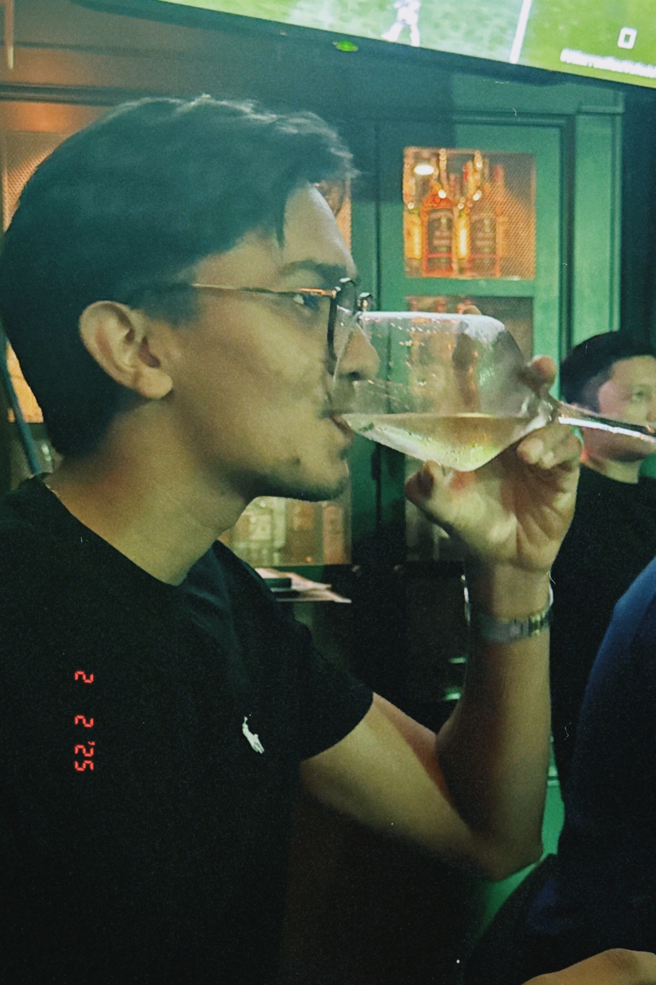 Film photo of Devam sipping a drink at a bar