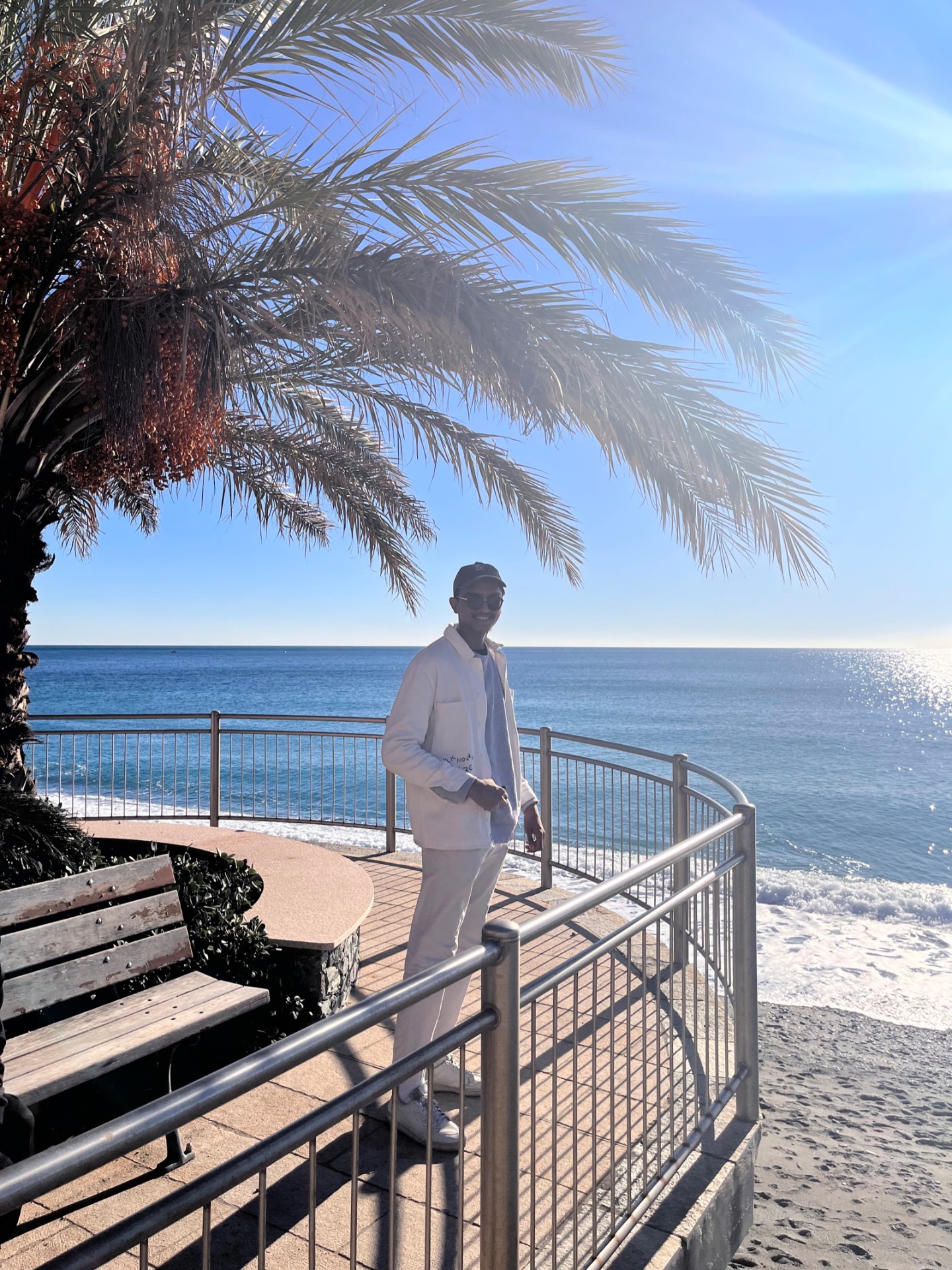 Devam in white by the sea under a palm tree in Nice